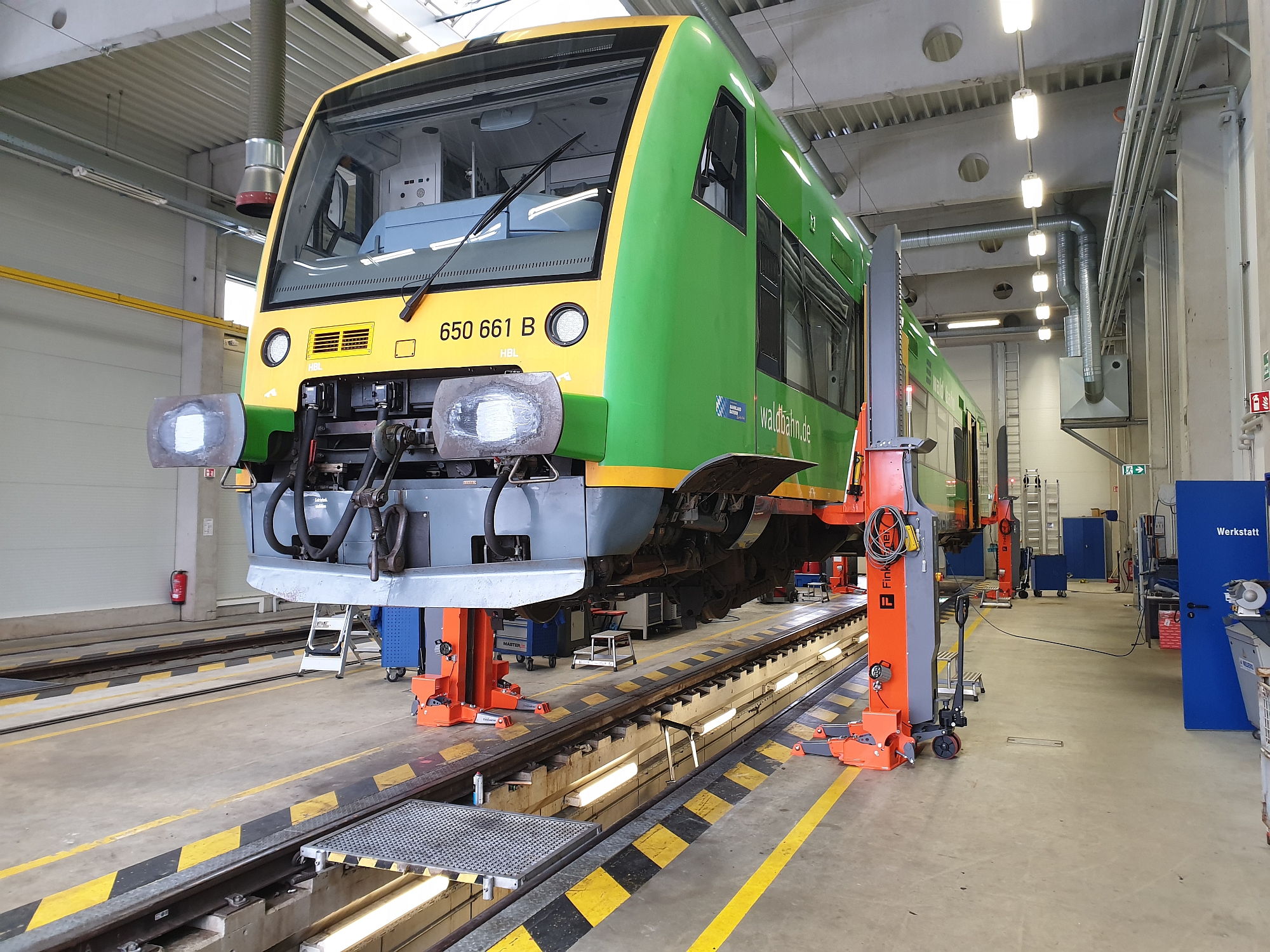 Colonnes mobiles équippées d'un bec ajustable avec un train régional dans l'atelier ferroviaire.